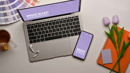 Top view of worktable with smartphone, laptop, supplies and flower decorated on the tableの写真素材