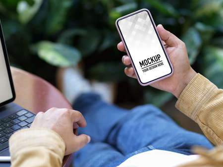 Close up view of male freelancer hand holding smartphone while relaxing in garden, include clipping pathの写真素材