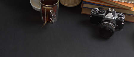 Close up view of worktable with copy space, camera, books and coffee cup in home office room