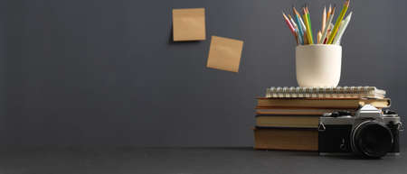 Close up view of study table with copy space, camera, books and stationery in home office roomの写真素材