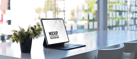 Side view of portable workspace with digital tablet, plant pot and copy space on white tableの写真素材