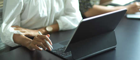 Close up view of female hand working with digital tablet on meeting table