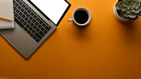 Top view of workspace with laptop, coffee cup, plant pot and copy space in home office, clipping...