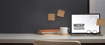 Close up view of worktable with laptop, notebooks, cup and copy space in home office room