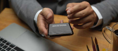 Close up view of businessman hands using smartphone while working in office room, clipping path