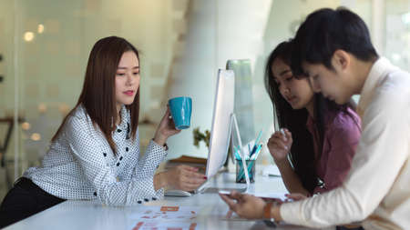 Portrait of UI developer team meeting on their project with paperwork and office supplies