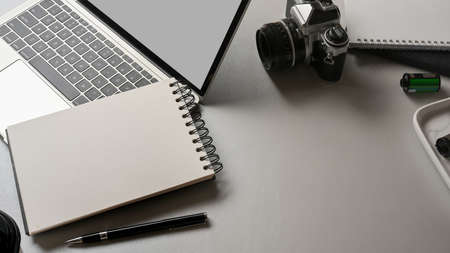 Top view of workspace with notebook, laptop, camera and copy space on white deskの写真素材