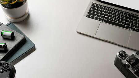 Top view of white worktable with laptop, camera, supplies and copy space