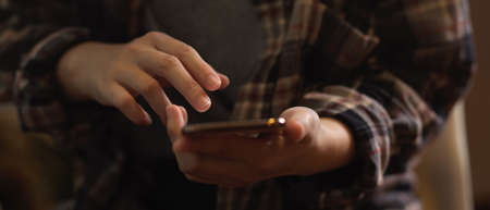 Close up view of female in Scott shirt hand using smartphone