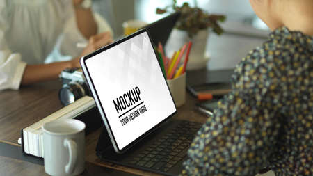 Side view of female hands working with tablet on worktable in meeting room, include clipping path