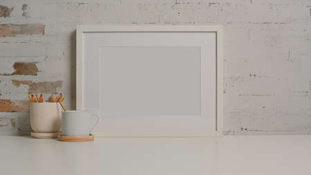 Close up view of white desk with mock up frame, stationery, cup and copy space in living roomの写真素材