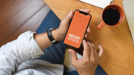 Top view of male hand using smartphone on wooden worktable, includeの写真素材