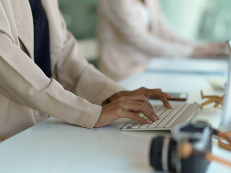 Side view of female hands typing on computer keyboard on the table in office room