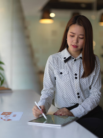 Portrait of female office worker working with digital tablet on white table in meeting roomの写真素材