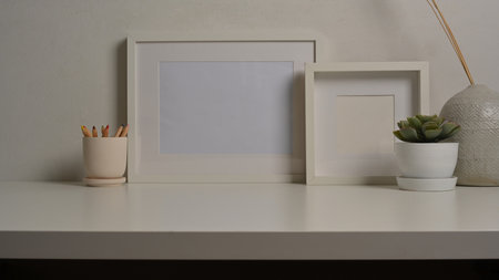 Close up view of home interior design with mock up frames, plant pot and vase on white desk