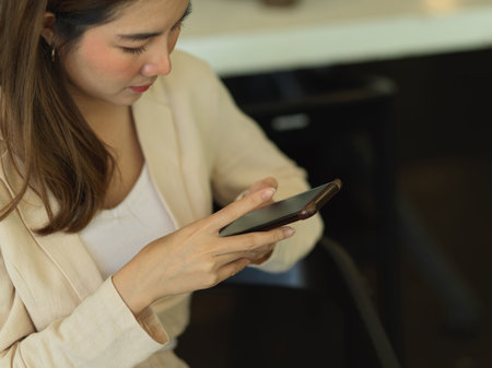 Portrait of businesswoman using smartphone while sitting in cafeteriaの写真素材