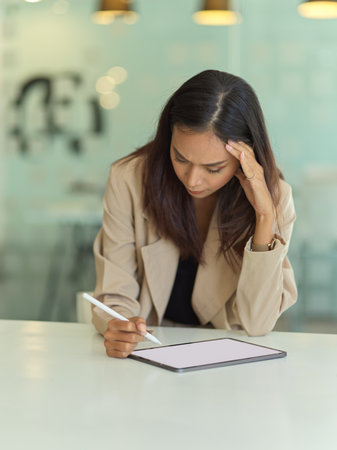 Portrait of seriously young businesswoman working with tablet in office roomの写真素材