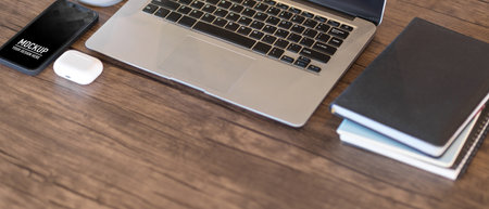 Cropped shot of wooden table with laptop, notebooks, smartphone and copy spaceの写真素材