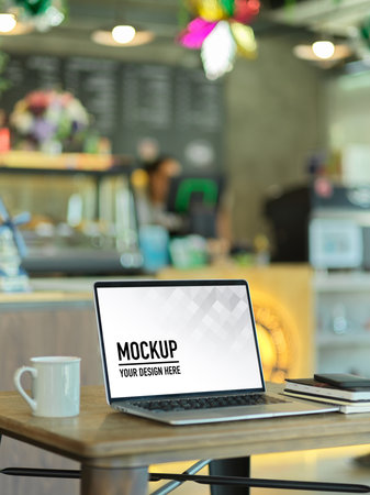 Cropped shot of portable workspace with laptop and coffee mug in cafe