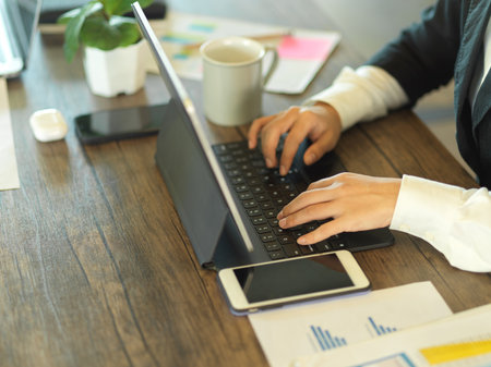 Cropped shot of female hands typing on tablet keyboard on wooden table in office roomの写真素材