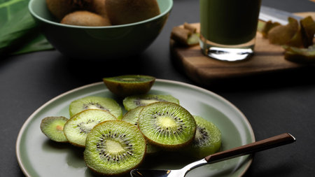 Close up view of sliced fresh kiwi fruit  on plate and healthy fresh kiwi smoothie in glass on...