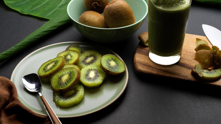 Close up view of healthy fresh kiwi smoothie in glass with whole and sliced kiwi fruit on the tableの写真素材