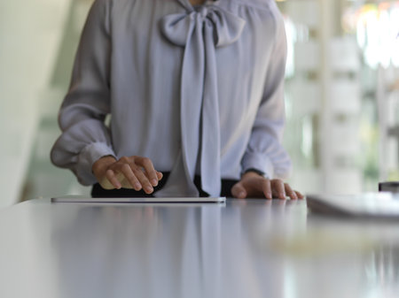 Close up view of female hand sing digital tablet on white worktable in office room