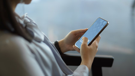 Side view of businesswoman hands using smartphone while relaxed sitting on arm chair