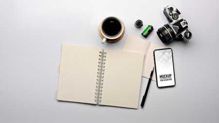 Top view of workspace with blank notebook, smartphone, camera and coffee cup, clipping path