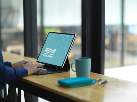 Side view of female hands working with digital tablet and stationery on wooden bar in cafeの写真素材