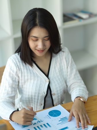 Portrait of businesswoman reading paperwork in office roomの写真素材
