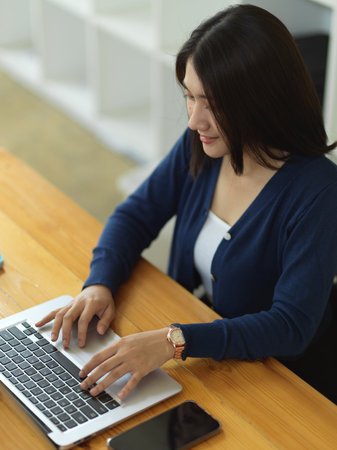 Top view of female university student doing assignment with laptop in libraryの写真素材