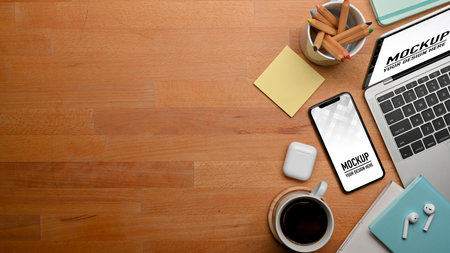 Top view of wooden table with smartphone, laptop, stationery, accessories and copy space