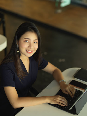 Portrait of businesswoman smiling to camera while working with laptop at workplace