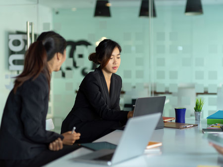 Side view of two businesswomen working on their project in meeting roomの写真素材