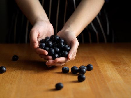 Close up view of female hands holding a lot of blueberries on wooden tableの写真素材