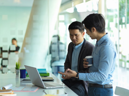 Portrait of two businessman talking to each other while take a coffee break in meeting roomの写真素材