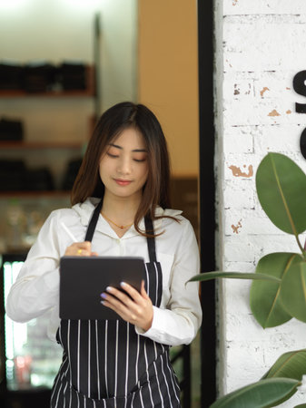 Portrait of young beautiful waitress taking an order on digital tablet in restaurantの写真素材