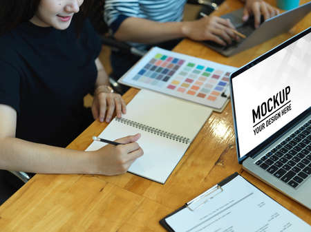Cropped shot of two designers working on their project with laptop and colour chart in office room