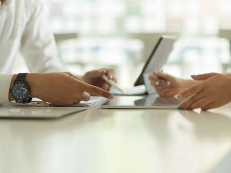 Side view of businesspeople hands working with digital tablet and document file on the table