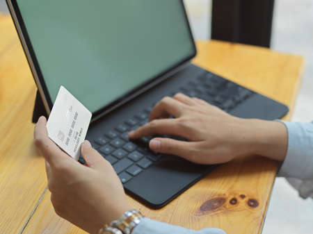 Cropped shot of female hand holding credit card while online paying on digital tablet