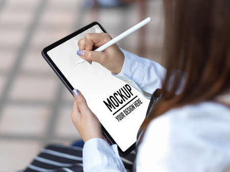 Close up view of female using digital tablet  with stylus pen in blurred backgroundの写真素材