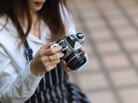 Cropped shot of female photographer with apron checking picture on digital camera while taking photo...