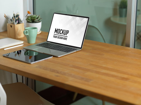 Cropped shot of workspace with laptop, tablet, supplies and copy space on wooden table, clipping pathの写真素材