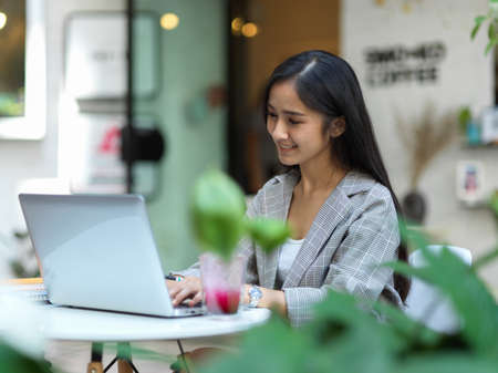 Portrait of businesswoman working with laptop on coffee table in front of cafeの写真素材