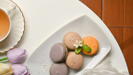 Top view of coffee table in living room with French colourful macarons and tea cup decorated with...