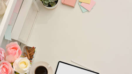Top view of feminine worktable with copy space, tablet, coffee cup, stationery and flower vase