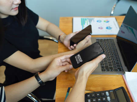 Side view of two businesspeople discussing on their work with smartphone and laptop on tableの写真素材