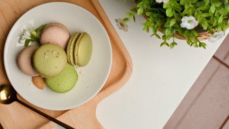 Top view of a plate of French Colorful Macarons on coffee table decorated with plant pot