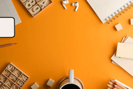 Top view of artist workspace with stationery, craft element, coffee cup and copy space on yellow...